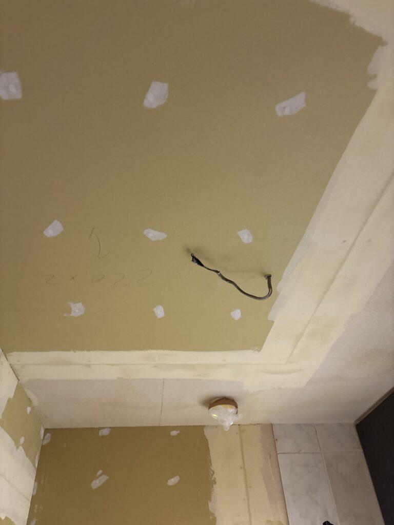 Prepared kitchen walls and ceiling with smooth finishing compound ready for wallpaper installation.