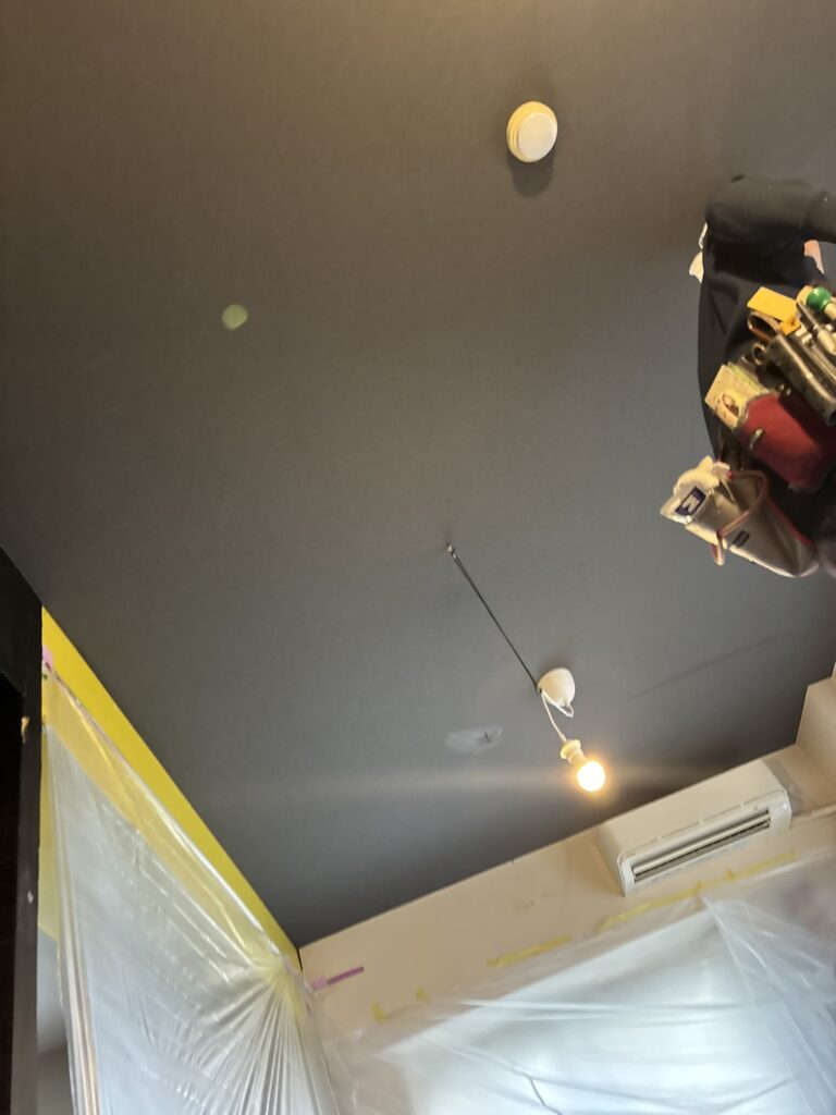 Close-up view of the completed black wallpaper on the living room ceiling.
