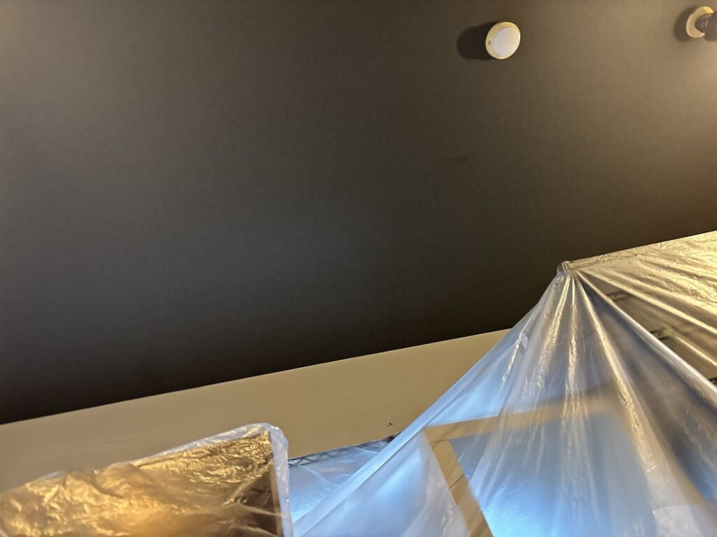 Finished living room ceiling with newly installed black wallpaper.