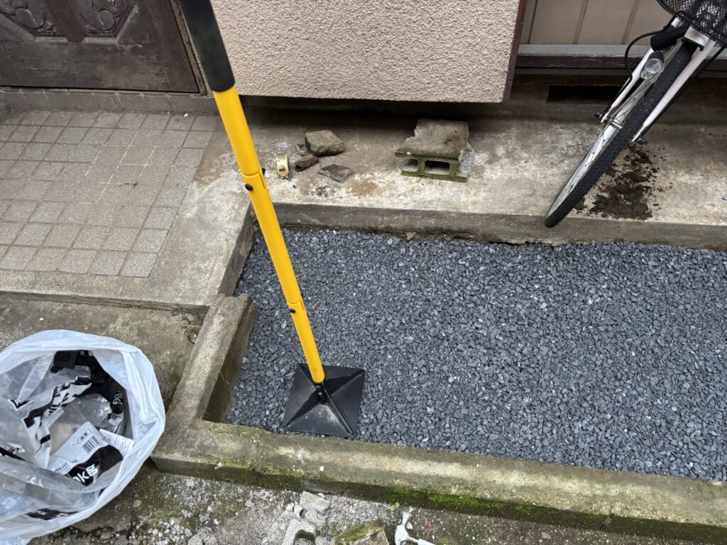 Crushed stone compacted with a manual hand tamper before concrete pouring.