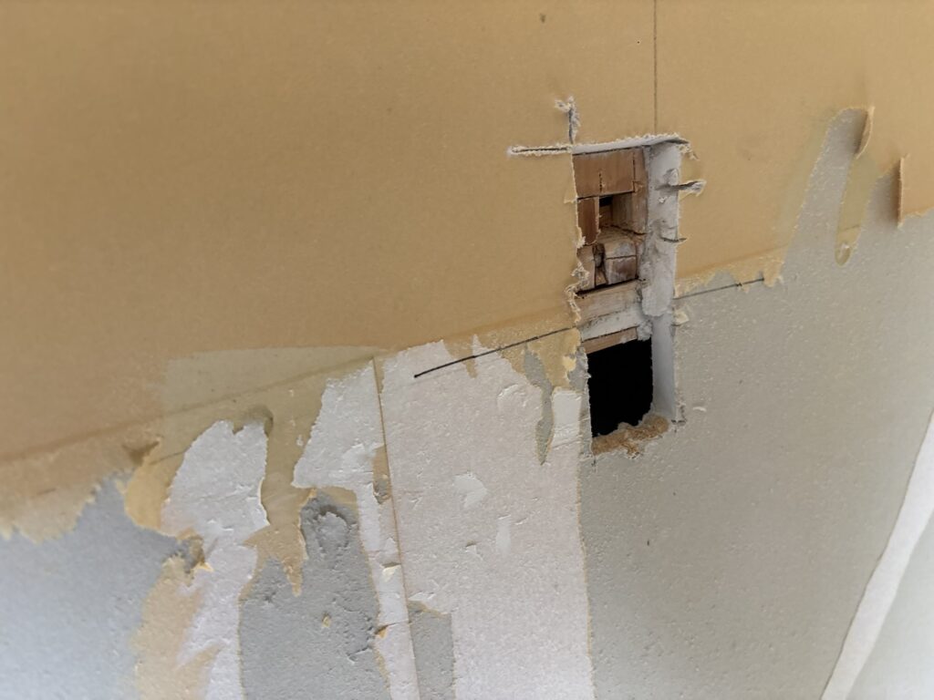 Hole in the kitchen wall left after an old electrical outlet was removed.
