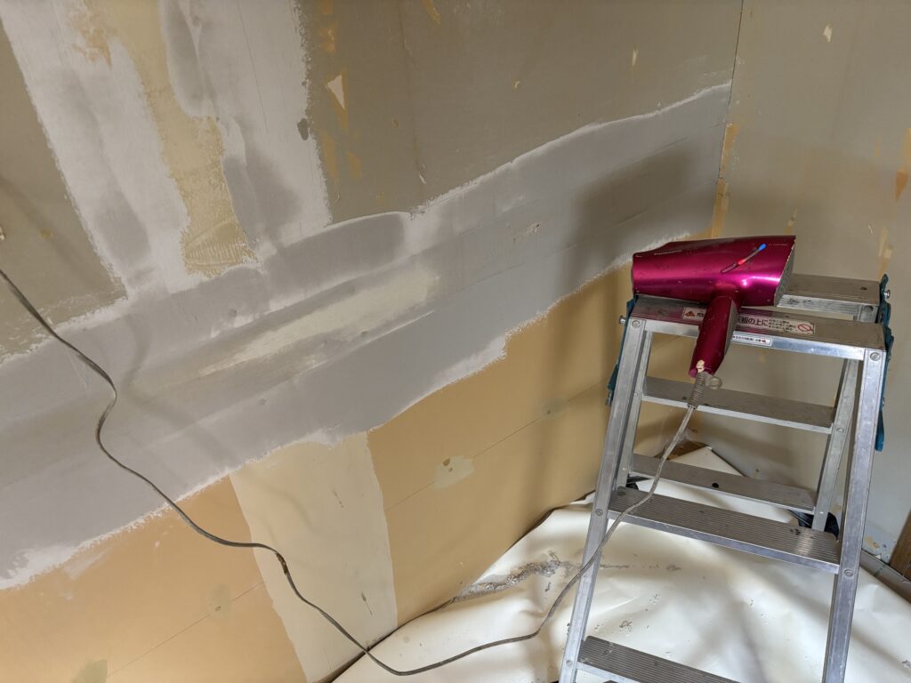 Hair dryer being used to dry joint compound on the kitchen wall during surface preparation.