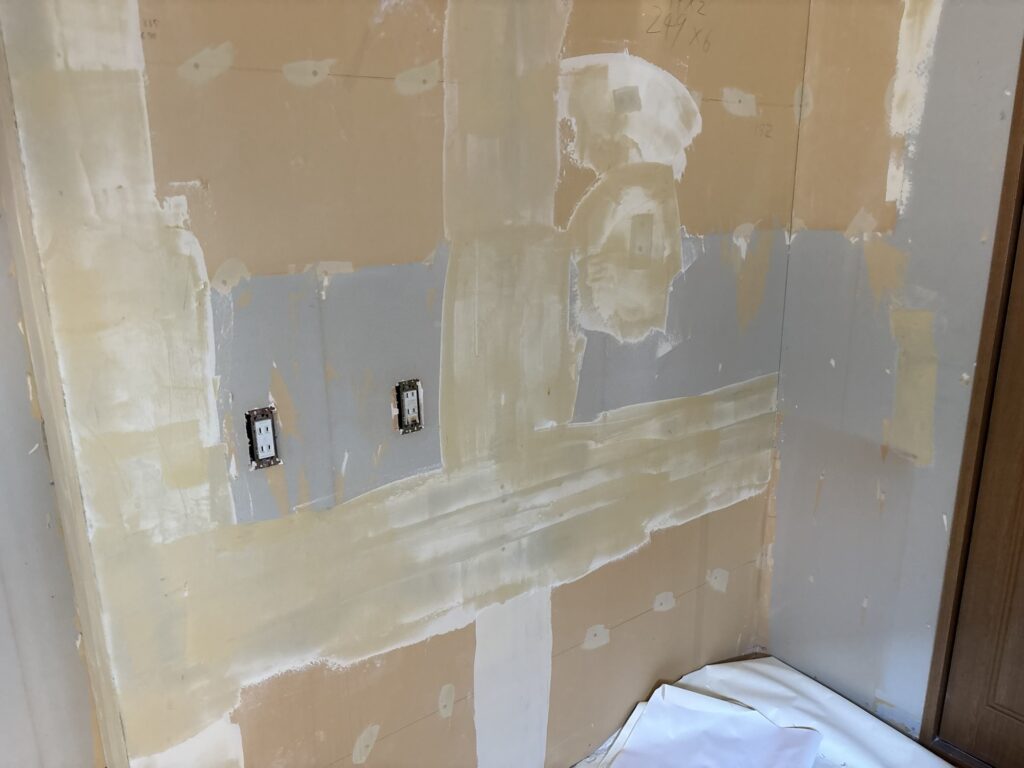 Kitchen wall after the finishing coat of joint compound was applied and smoothed before wallpaper installation.