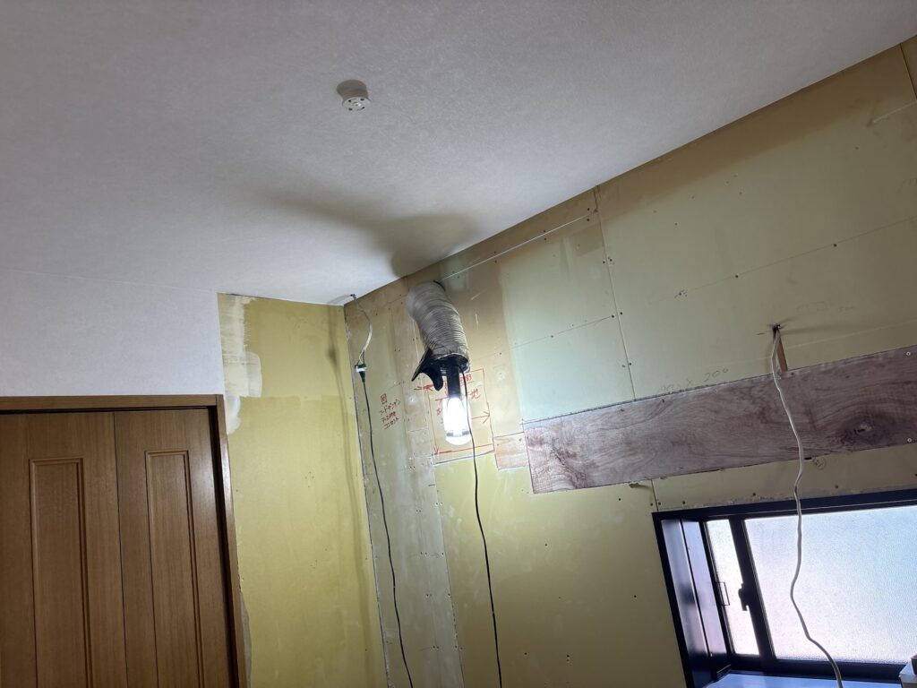 Completed kitchen wallpaper installation with sections left uncovered for future kitchen panels and wall cabinets.