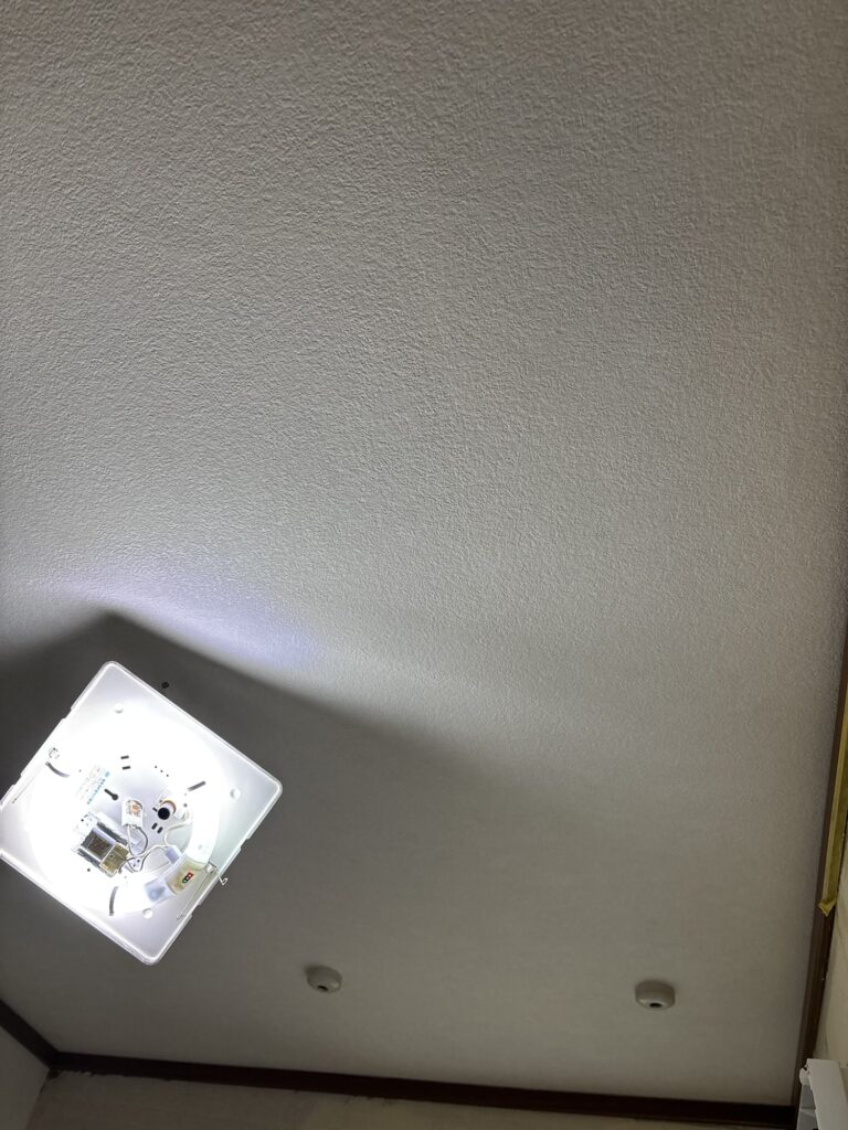 Completed wallpaper installation on the ceiling of a renovated washroom.