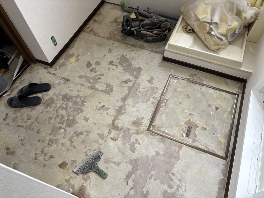 Washroom floor after removing remaining old wallpaper backing paper before cushion flooring installation.