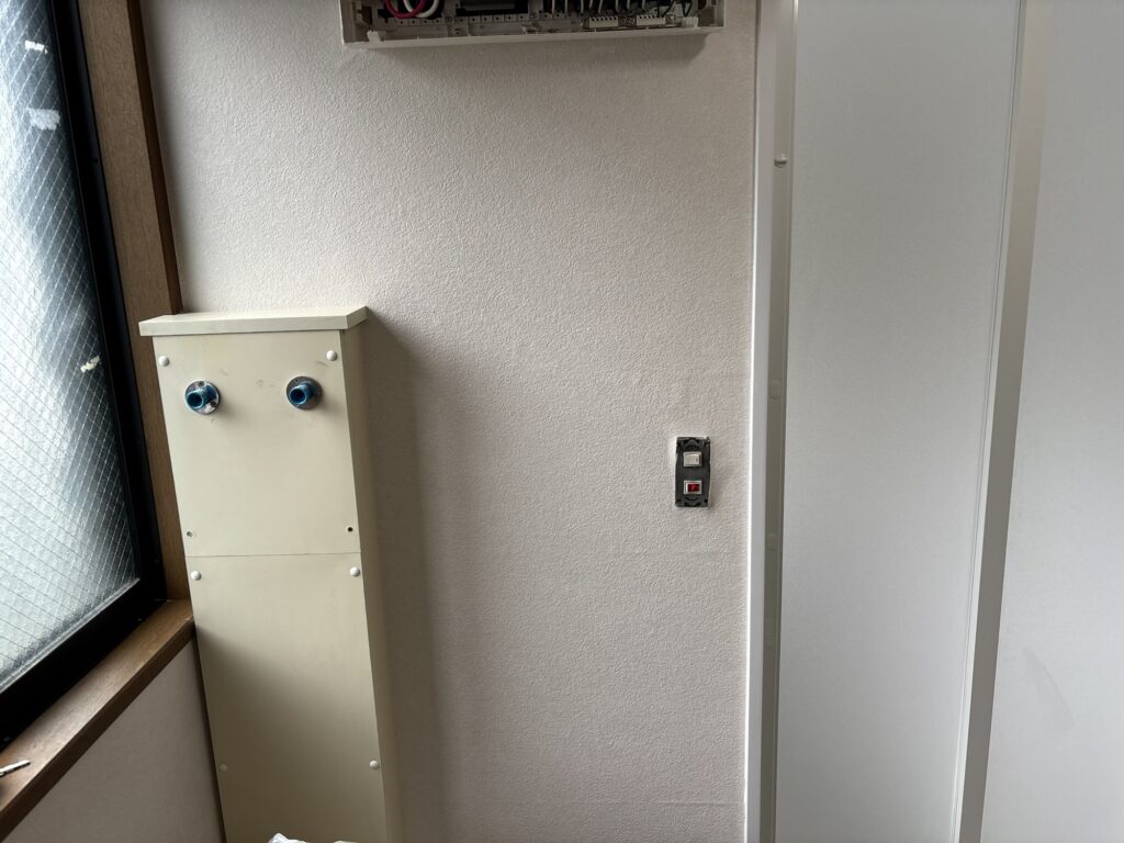 Finished wallpaper around an electrical distribution panel and bathroom entrance frame in a Japanese washroom.