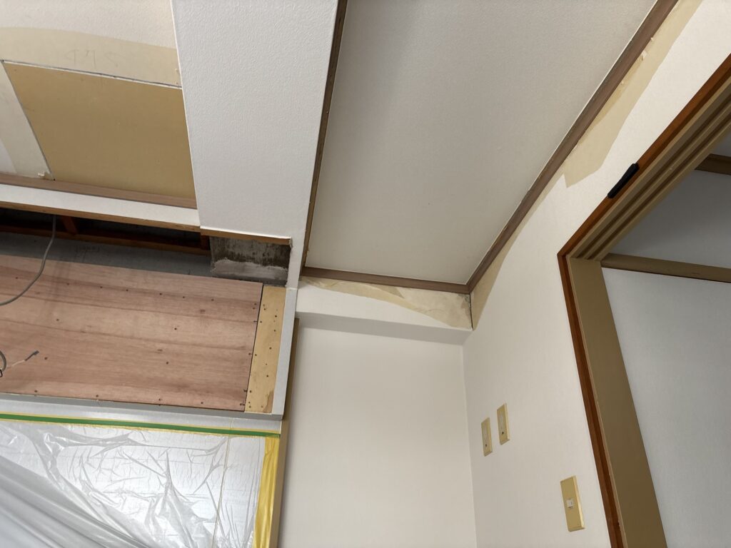 Vacant apartment living room prepared for ceiling and wall wallpaper replacement.