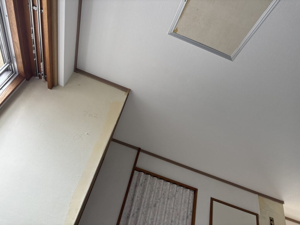 Close-up view of newly installed white patterned wallpaper on an apartment ceiling.