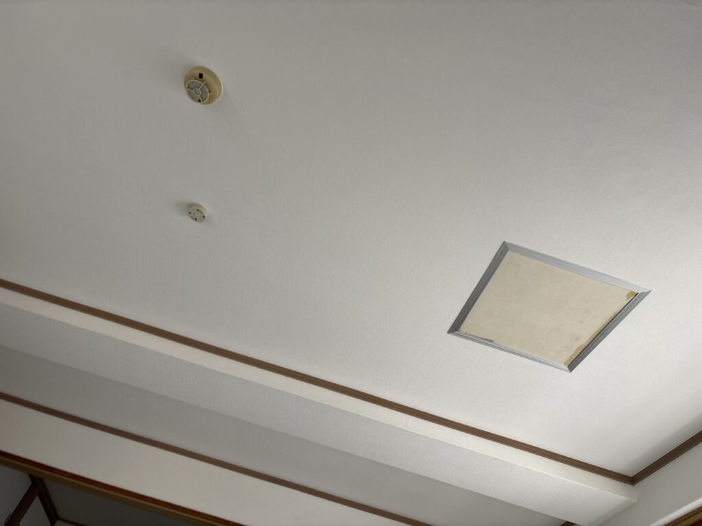 Completed white grid-pattern wallpaper installation on the living room ceiling.