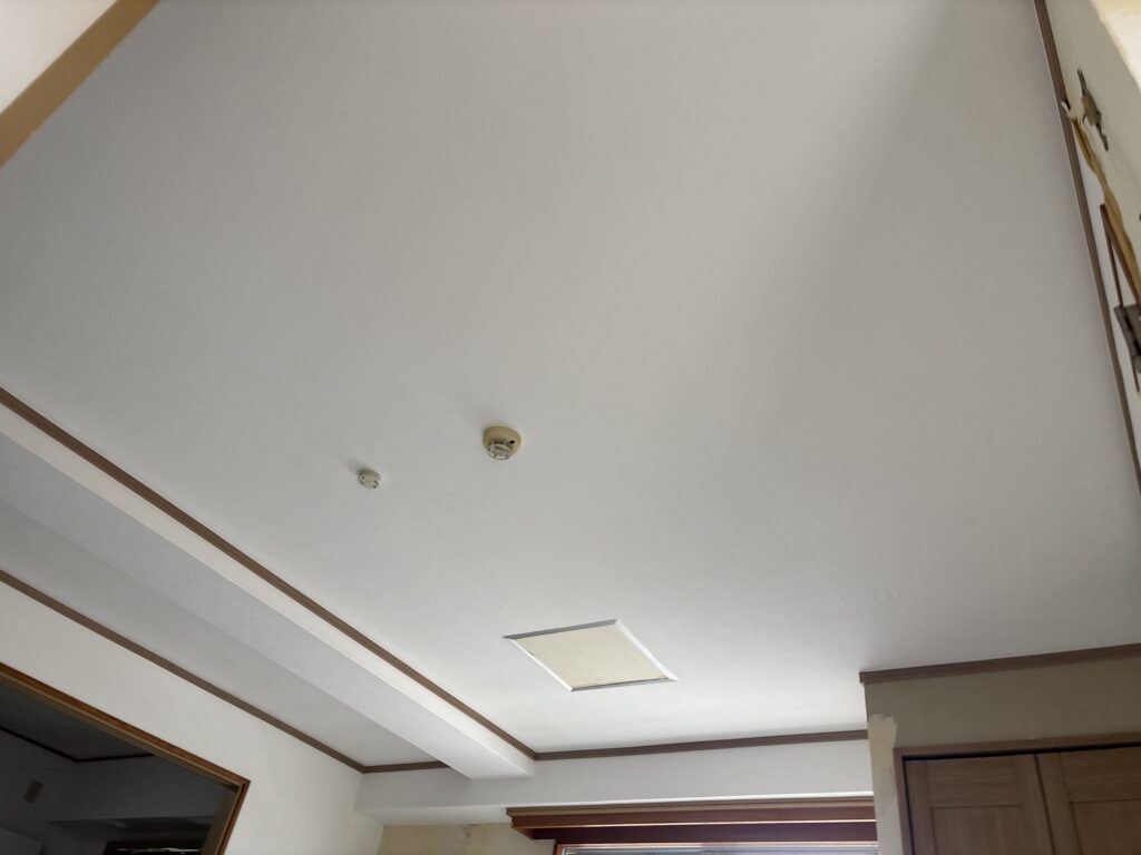 Finished apartment living room ceiling with newly installed white grid-pattern wallpaper.