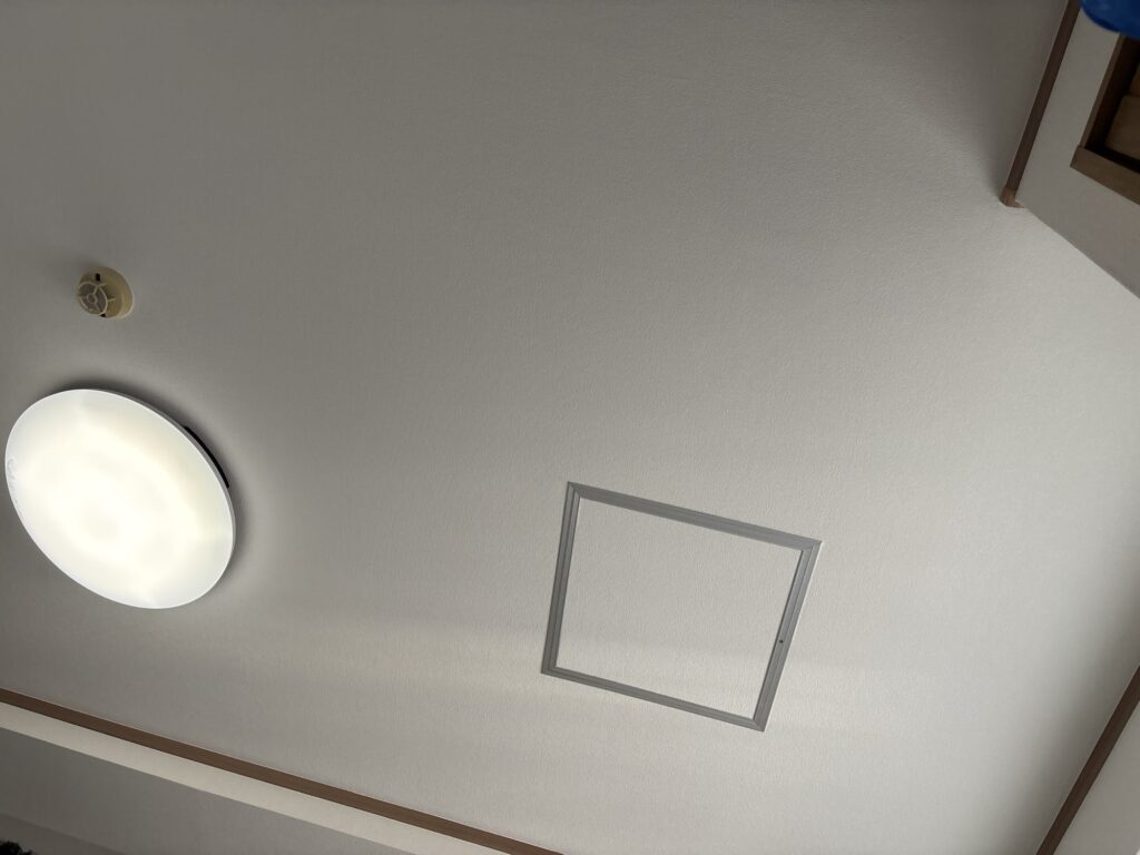 Detailed view of completed ceiling wallpaper installation with finished edges around the room.