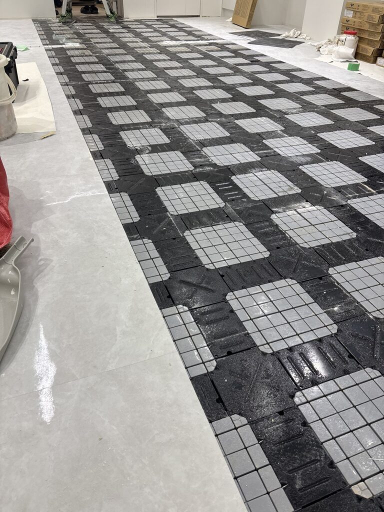 Worker removing old vinyl floor tiles during a commercial store renovation.