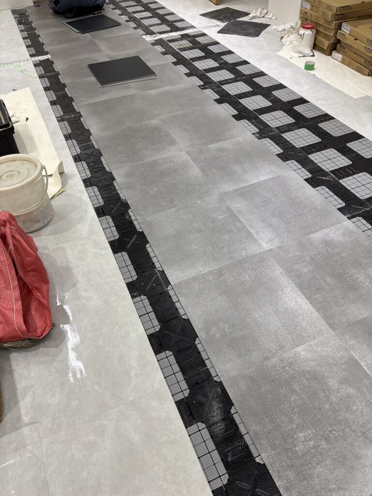 Two rows of new gray vinyl tiles installed on a commercial store floor.