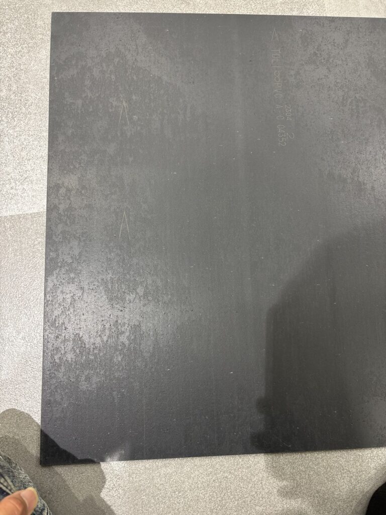 Directional arrows printed on the back of a vinyl floor tile during commercial flooring installation.