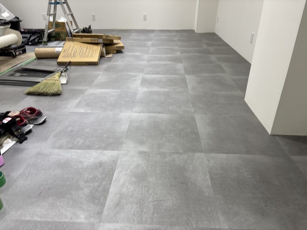 Wide view of completed gray vinyl tile flooring in a commercial store renovation.