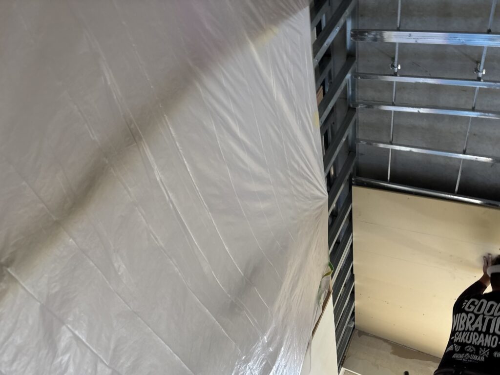 Carpenter installing gypsum boards on the living room ceiling of a Japanese apartment.