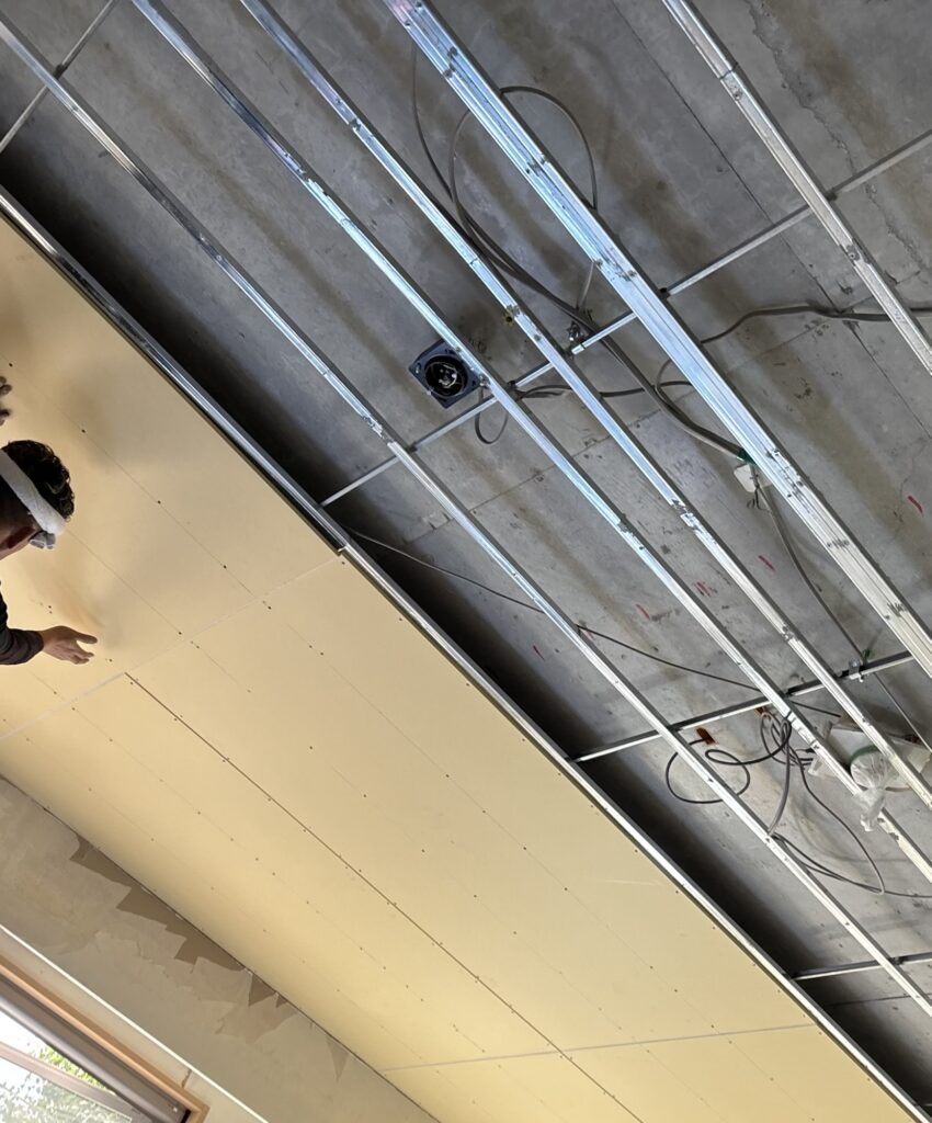 Carpenter working on the installation of ceiling boards in the living room of a 2LDK apartment.