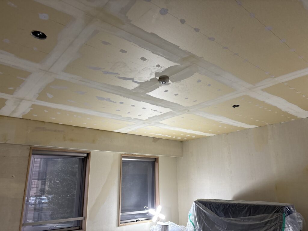 Base coat putty applied to gypsum board joints on the living room ceiling.