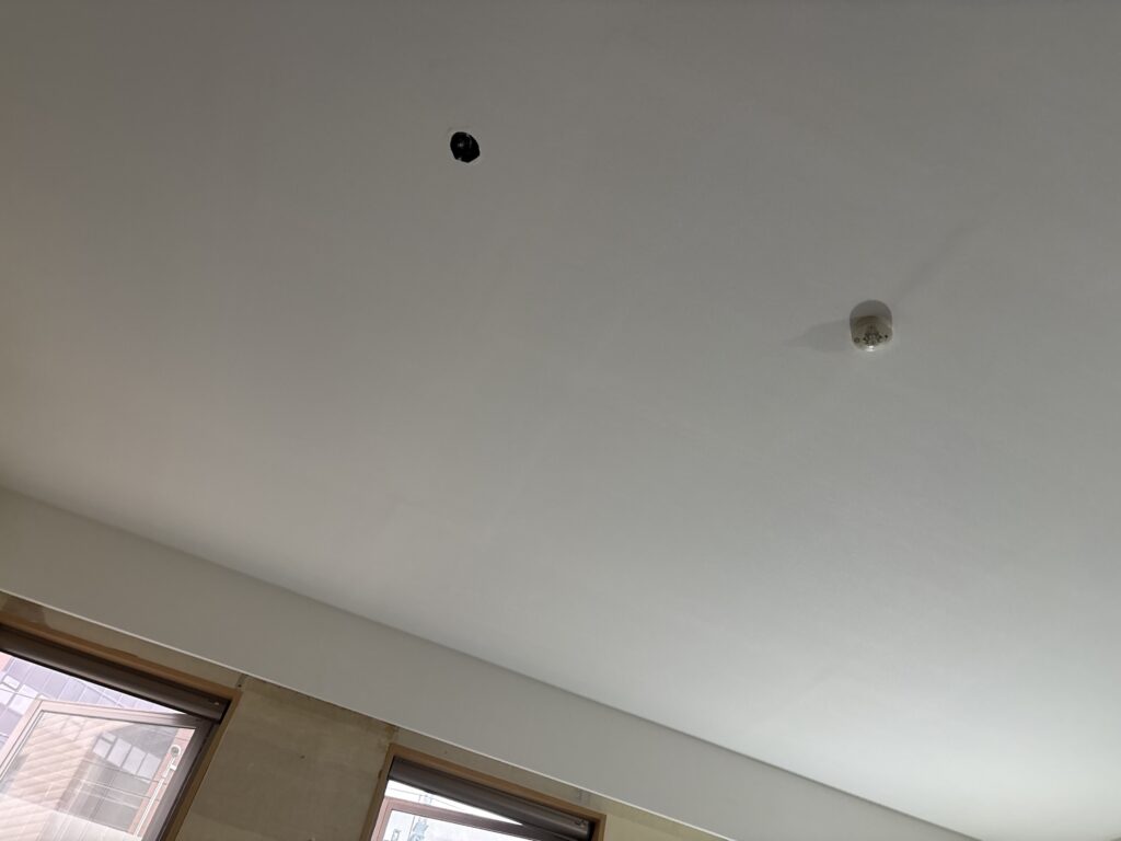 Completed white stone-textured wallpaper installation on the living room ceiling of a Japanese apartment.