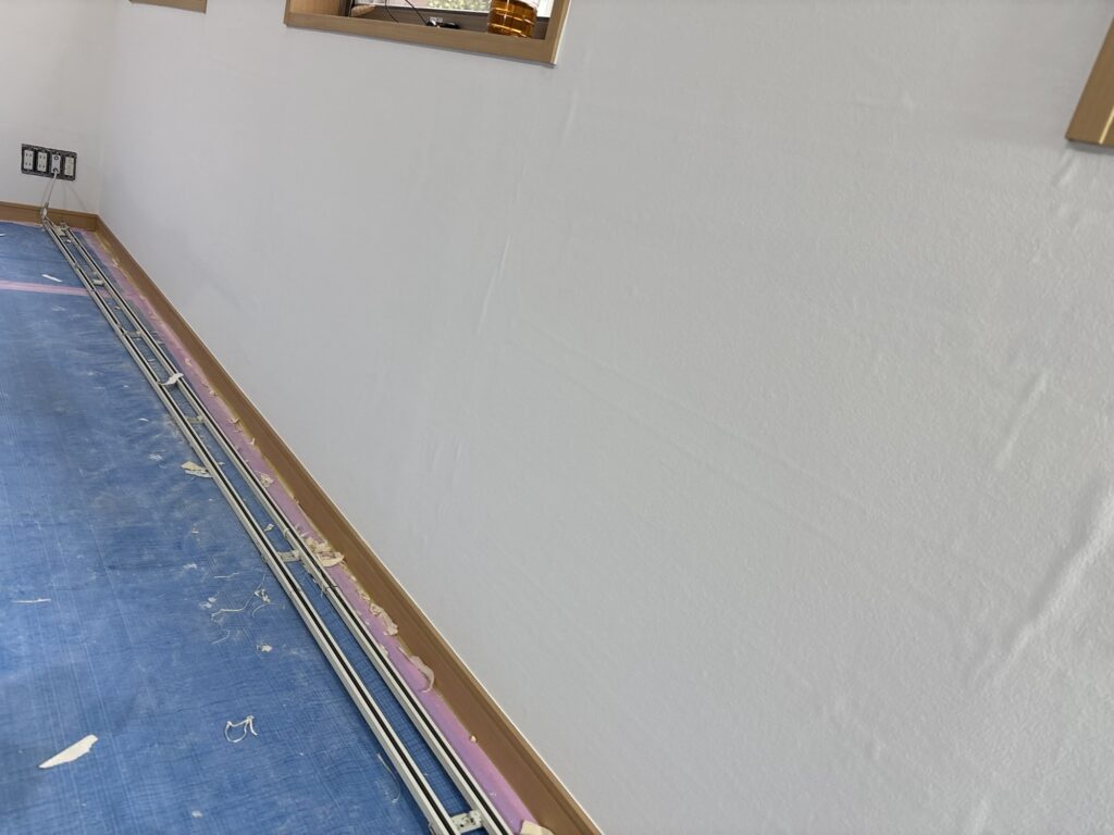 Completed wallpaper installation on a living room wall in a Japanese 2LDK apartment.