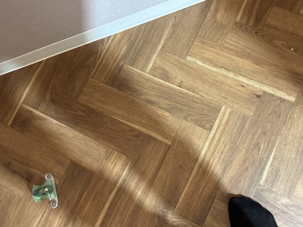 Second view of completed herringbone cushion flooring in a renovated apartment toilet.
