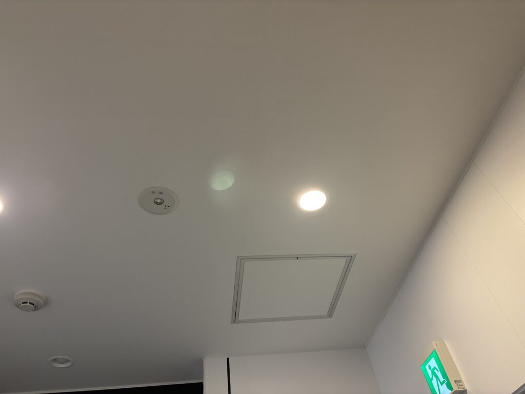 Completed white wallpaper installation on the hallway ceiling of an eighth-floor commercial space in Japan.