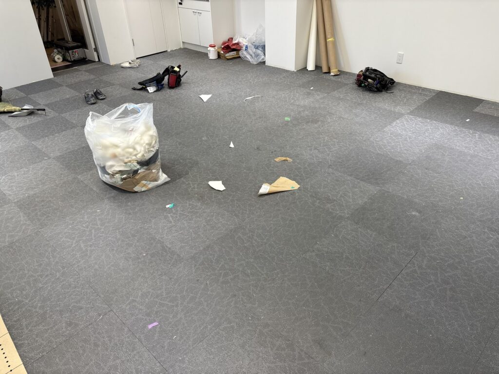 Commercial interior room before floor tile replacement, showing the existing tiled floor and surrounding walls.