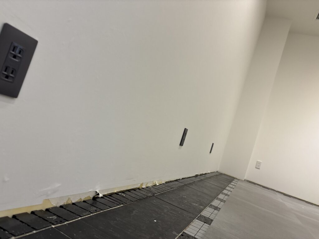 Rows of new floor tiles installed across a commercial room, with the remaining section near the wall prepared for fitting cut tiles.