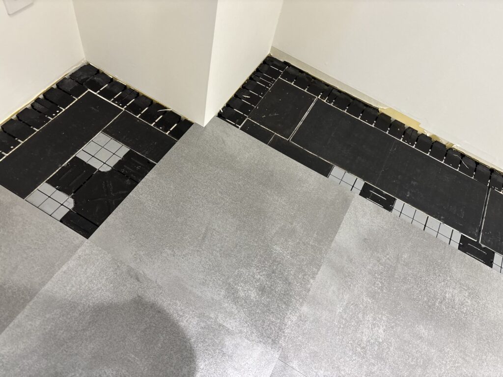 A worker installing and adjusting a floor tile at an outside corner during a commercial floor renovation in Japan.