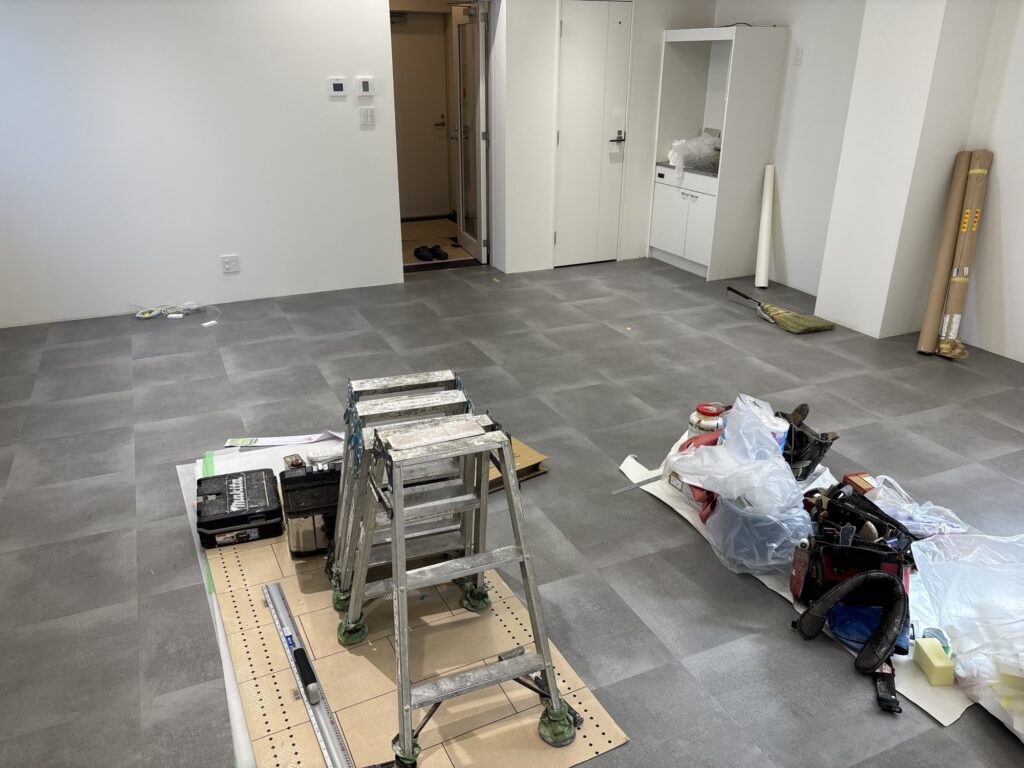 Completed square floor tile installation in a commercial interior, showing the finished tiled surface near the room’s perimeter.