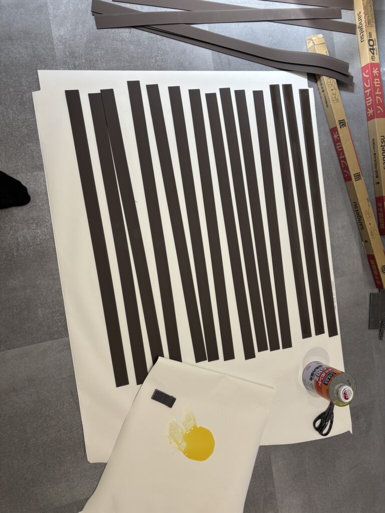 A worker applying adhesive to the back of a flexible soft baseboard before attaching it to the wall above the new floor tiles.