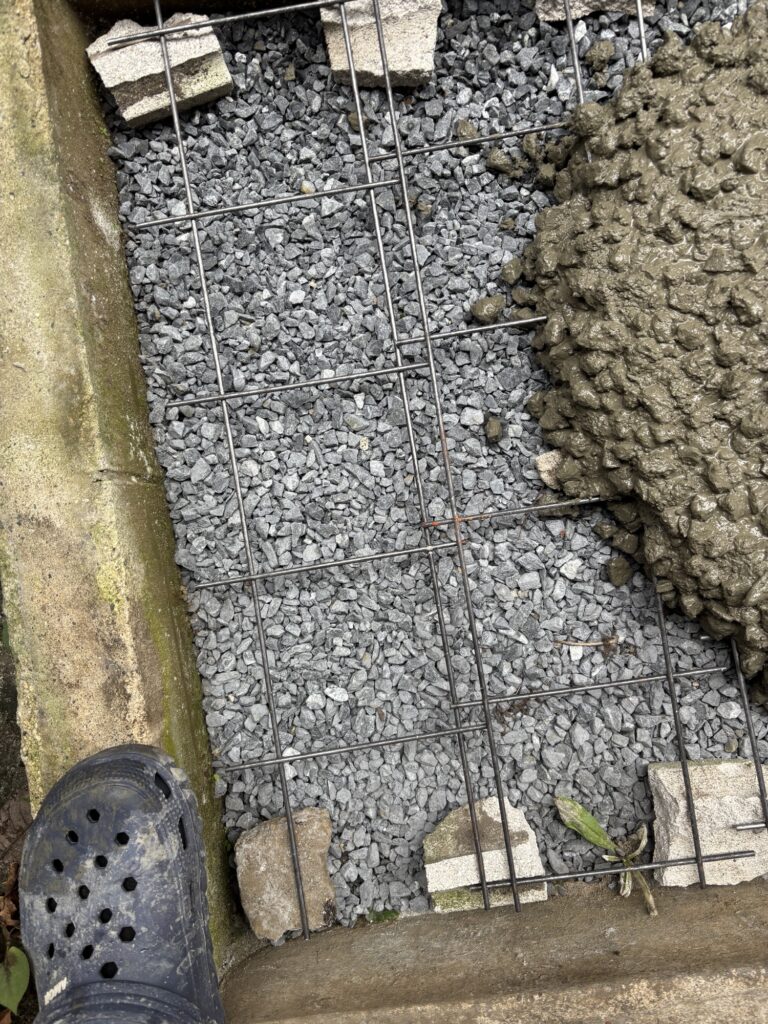 Wire mesh positioned over the prepared gravel base for a DIY concrete slab.