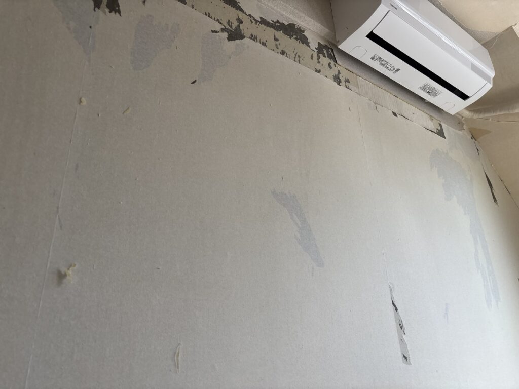 Condominium wall after old wallpaper has been stripped, exposing the remaining backing paper.