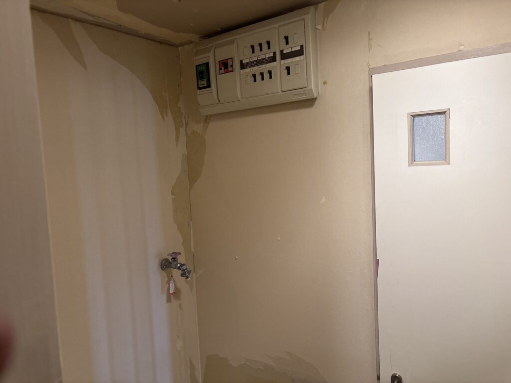 Washroom interior after old wallpaper removal during a Japanese condominium renovation.