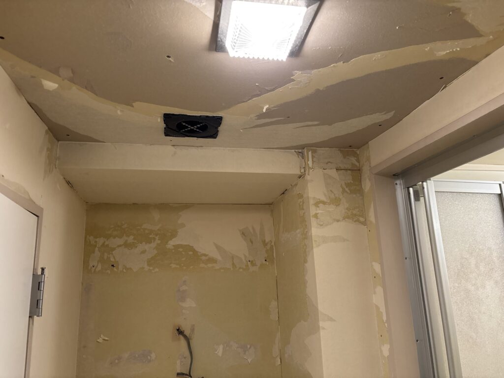 Another view of the washroom walls with the old wallpaper removed and the backing layer exposed.